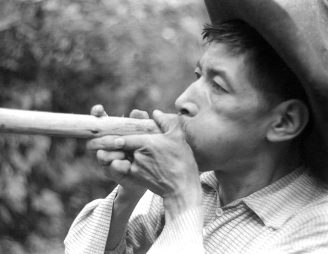 Photograph of a Mayan man demonstrating how to use a blowgun, one of the most effective Mayan weapons